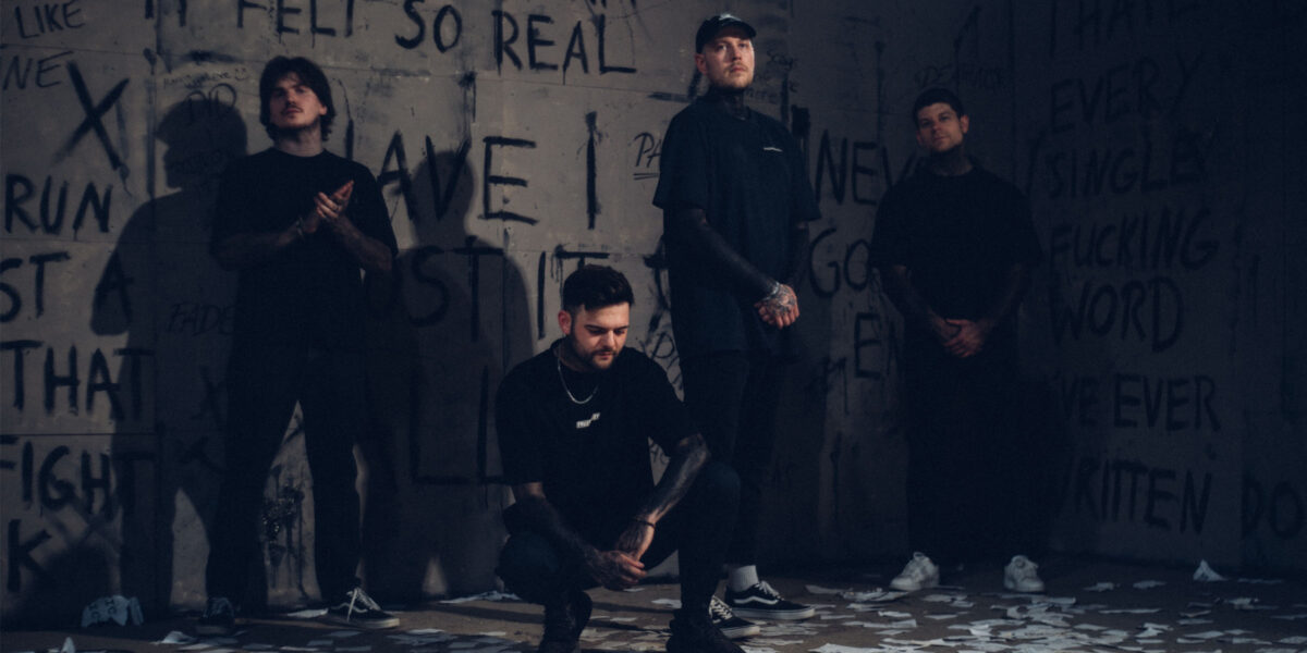 Die vier Bandmitglieder posieren vor einer mit Graffiti beschriebenen Wand. Drei stehen weiter im Hintergrund, ein Mann hockt weiter vorne in der Mitte. Auf dem Boden liegen zahlreiche verstreute Papierstücke.