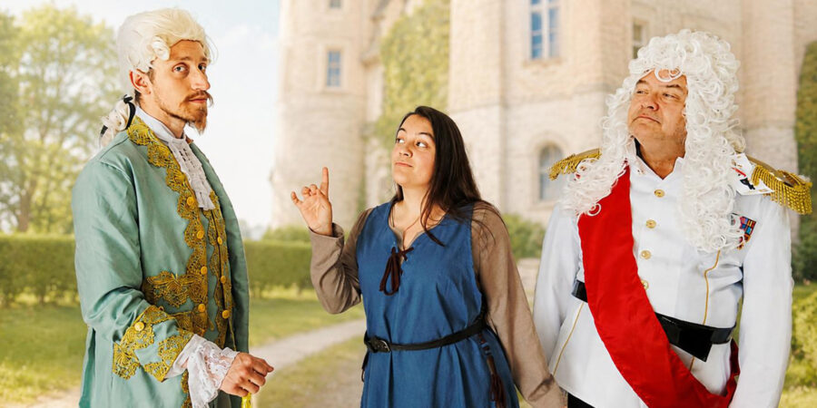 Vor einer KI-generierten Schlosslandschaft stehen drei Schauspielende. Links ein hagerer, jüngerer Mann, in der Mitte eine jüngere Frau und rechts ein älterer Herr als Kaiser. Sie alle tragen Perücken und Kostüme im Barockstil.